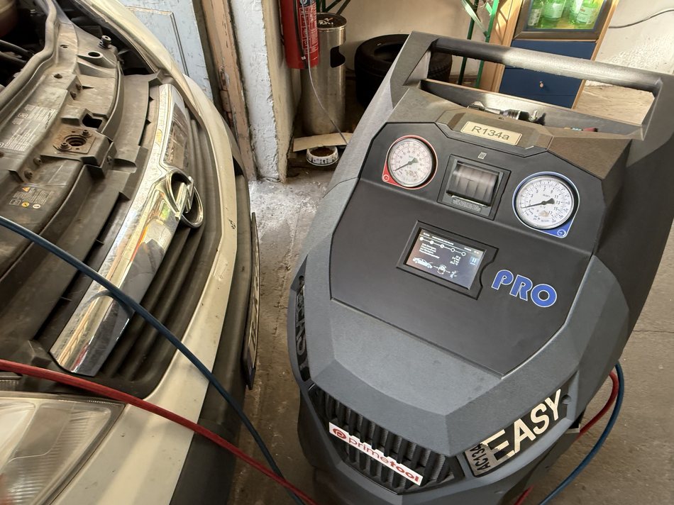 Klimaanlagen-Servicegerät neben einem Fahrzeug mit geöffneter Motorhaube